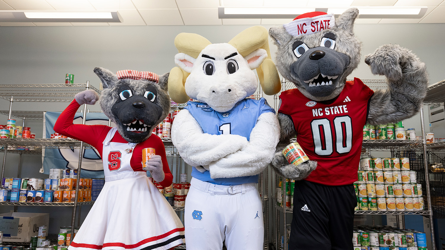 NC State and UNC's mascots gather in front of shelves of canned food.