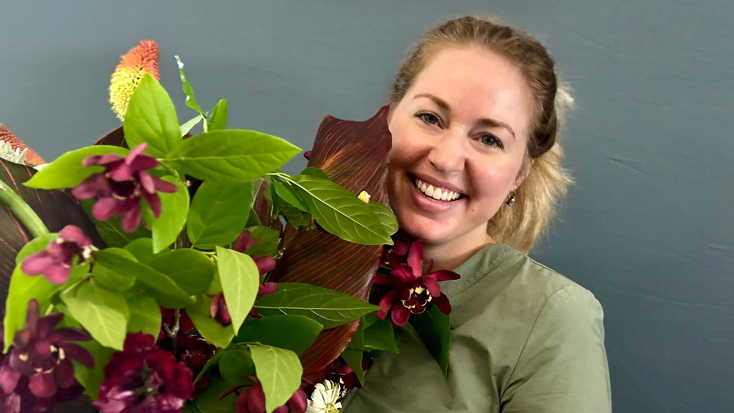 a woman poses with a large arrangement of flowers