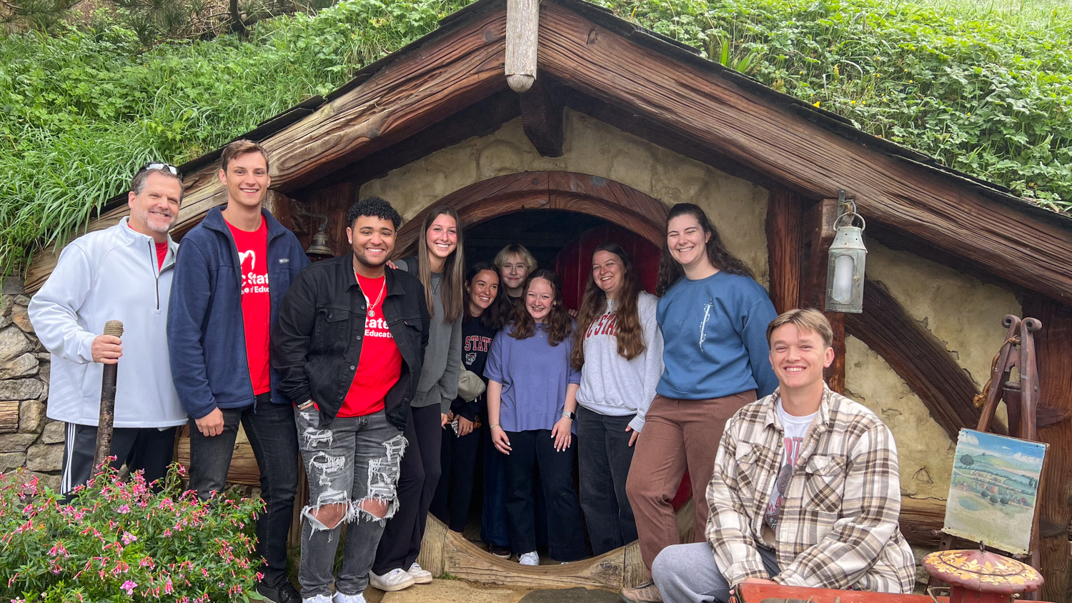 A group of College of Education students standing in front of a home in Hobbiton.