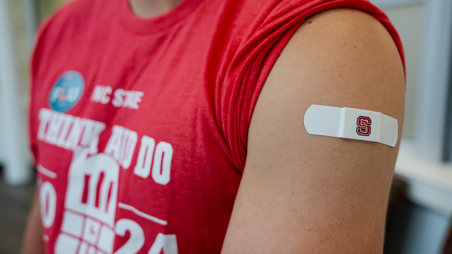An NC State student's arm displays an NC State band-aid after receiving a flu shot.