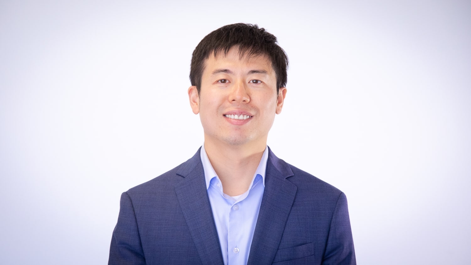 Yang Zhang stands in front of a white background.