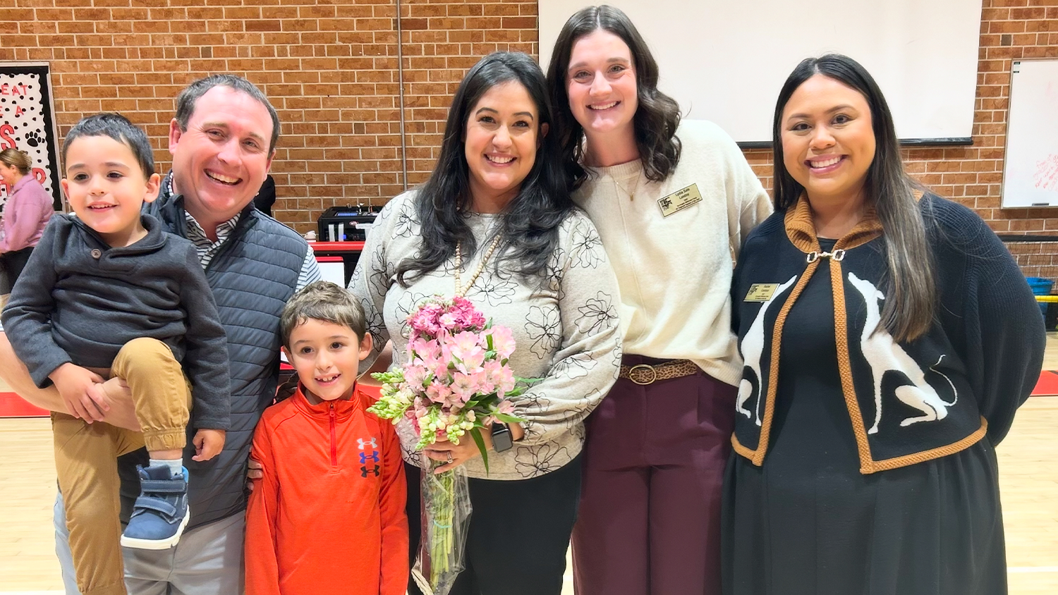 NC State College of Education alum Nishelle Henson, pictured in the center holding flowers alongside, from left to right: Left to Right is her 3-year-old son, Jacob Henson, who is being held by her husband, Jon Henson; her 7-year-old son Noah Henson, Me, Lydia Sale Lunday (the 2025 Western Region Teacher of the Year), and Rachel Candaso (the current NC Teacher of the Year)