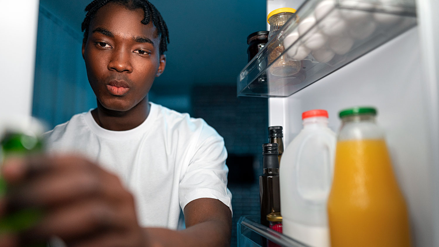 Young man reaching for an item in the refrigerator