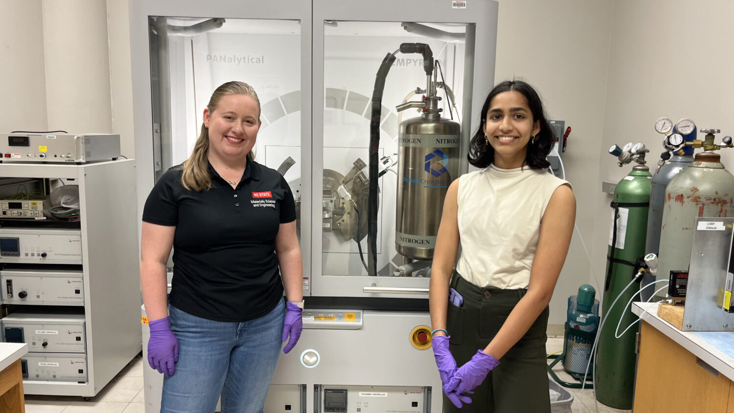 Lauren Dunlap (left) and Keertana Ramars (right) standing in front of the XRD Lab at the Analytical Instrumentation Facility