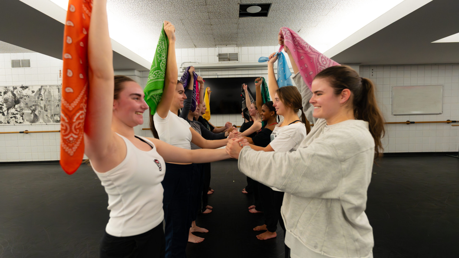 Students in two rows hold multi-colored scarves above their heads at a Panoramic Dance Project rehearsal.
