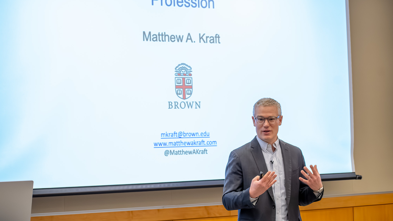 Brown University Professor Matthew A Kraft stands in front of a projected presentation at the College of Education Research Celebration.