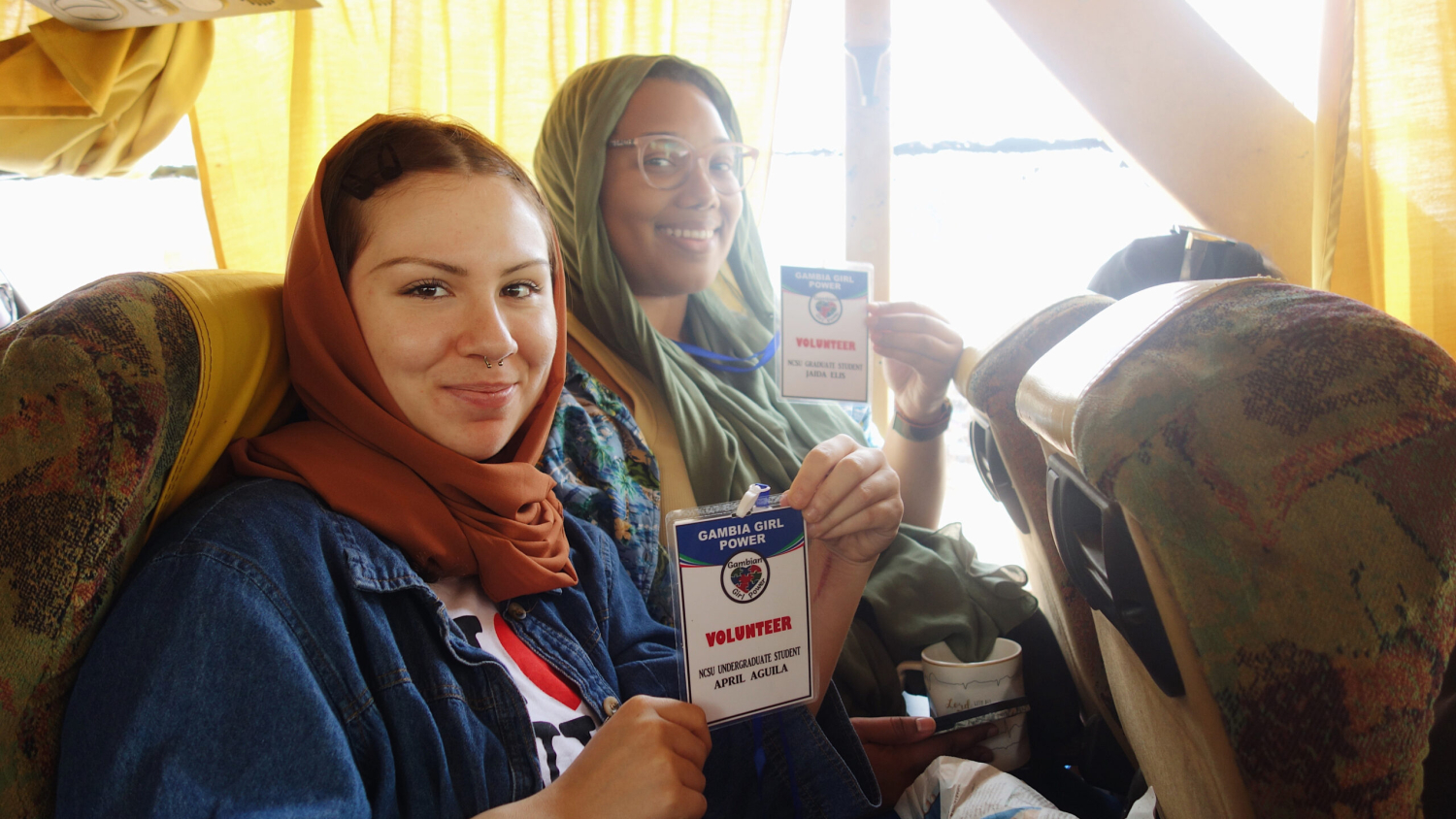 April Aguila and Jaida Ellis smile and hold up Gambian Girl Power name tags during an experiential learning trip to Gambia.