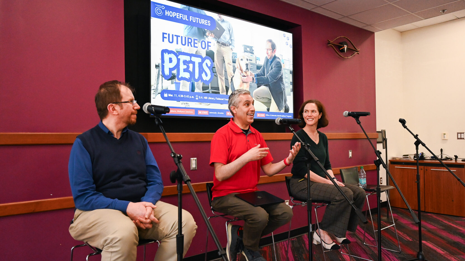 three panelists sit by microphones