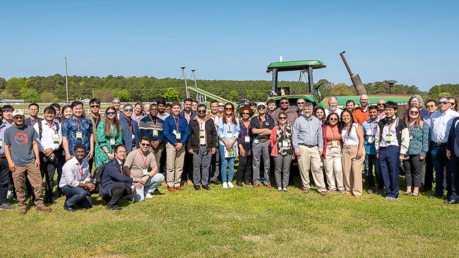 a group of people stand in front of a tractor in a field