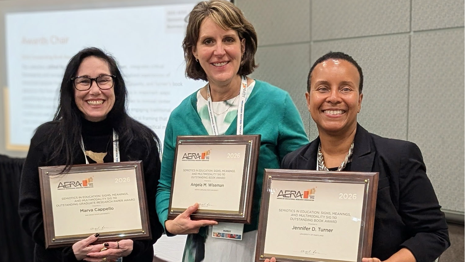 Associate Professor Angela Wiseman stands with her co-authors holding the award they received from the American Educational Research Association (AERA) Semiotics in Education Special Interest Group (SIG).