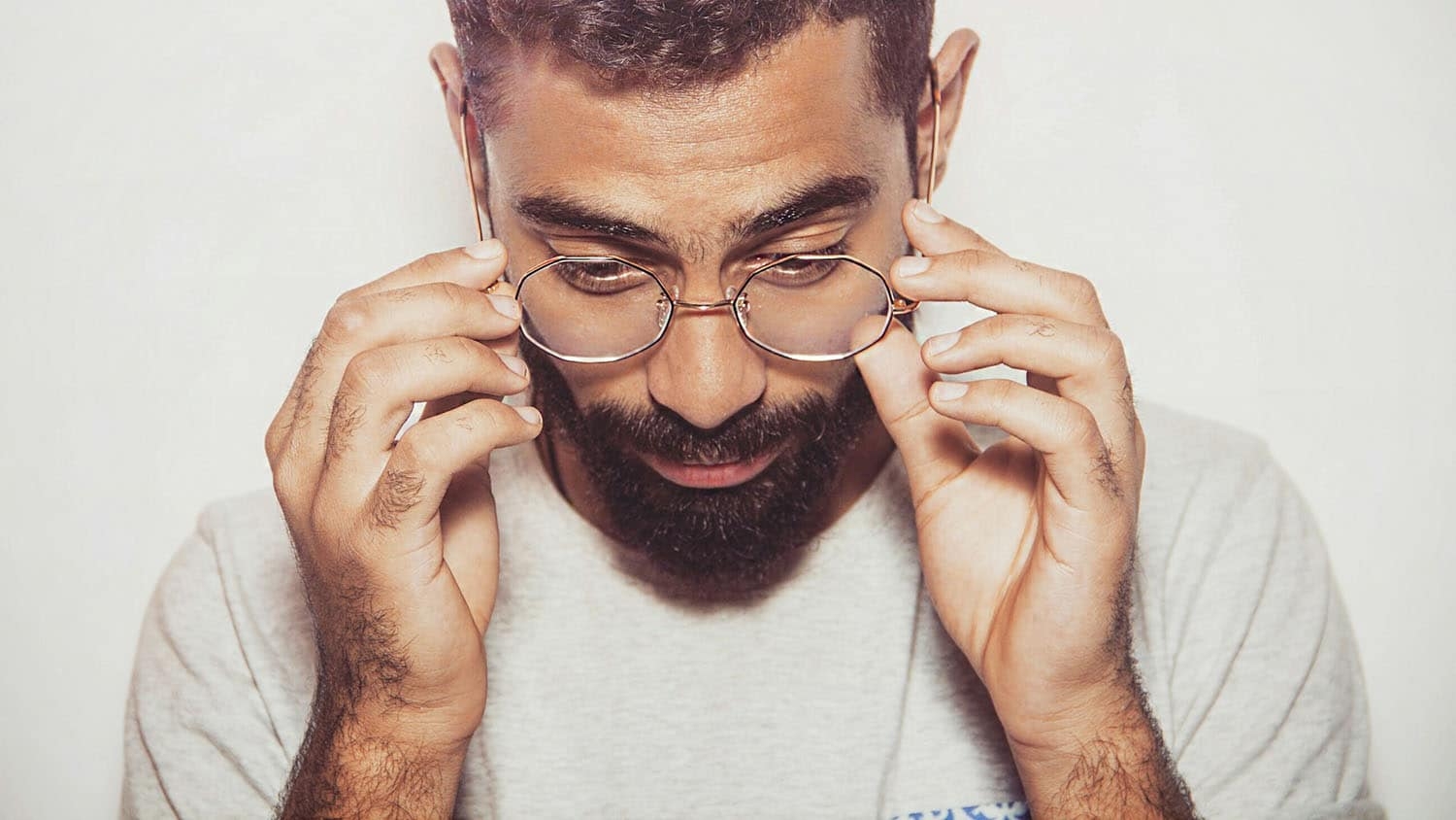 a man peers down through his glasses as if struggling to read something