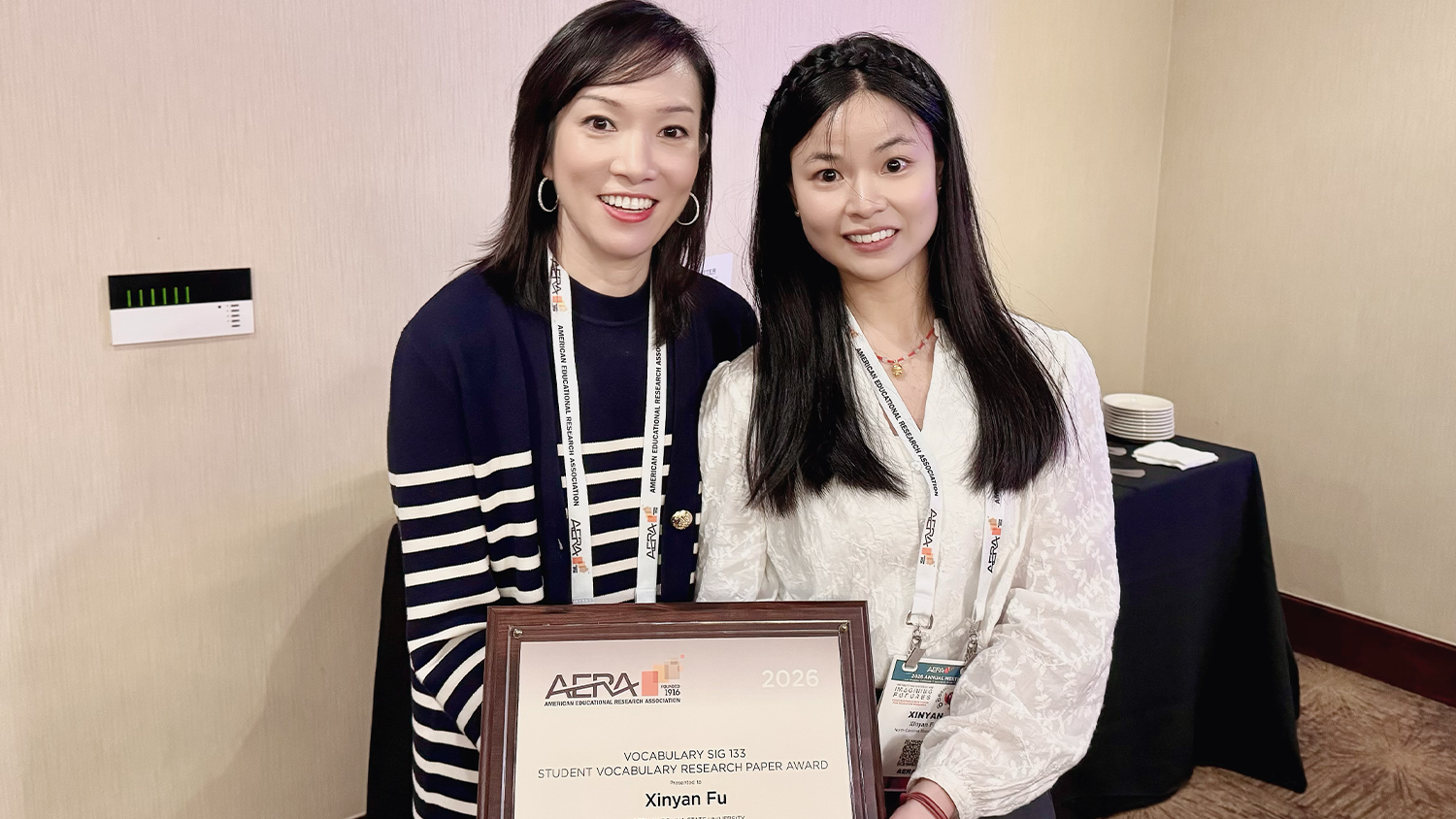 Doctoral student Xinyan Fu stands with Associate Professor Jackie Relyea as they hold Fu's AERA award.