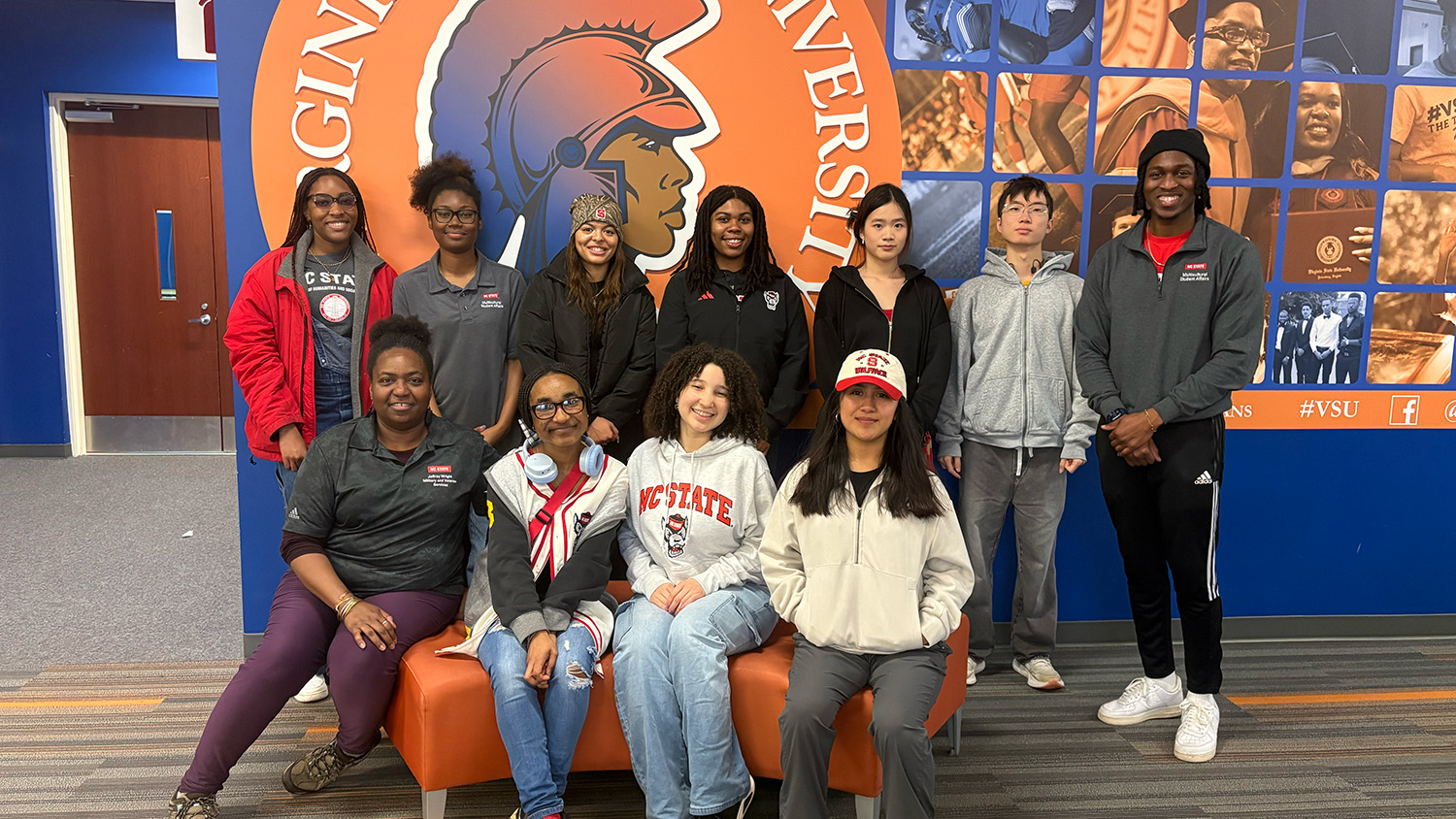 Students and staff members on a Cultural Immersion Trip to Richmond gather for a group photo in front of a Virginia State sign.