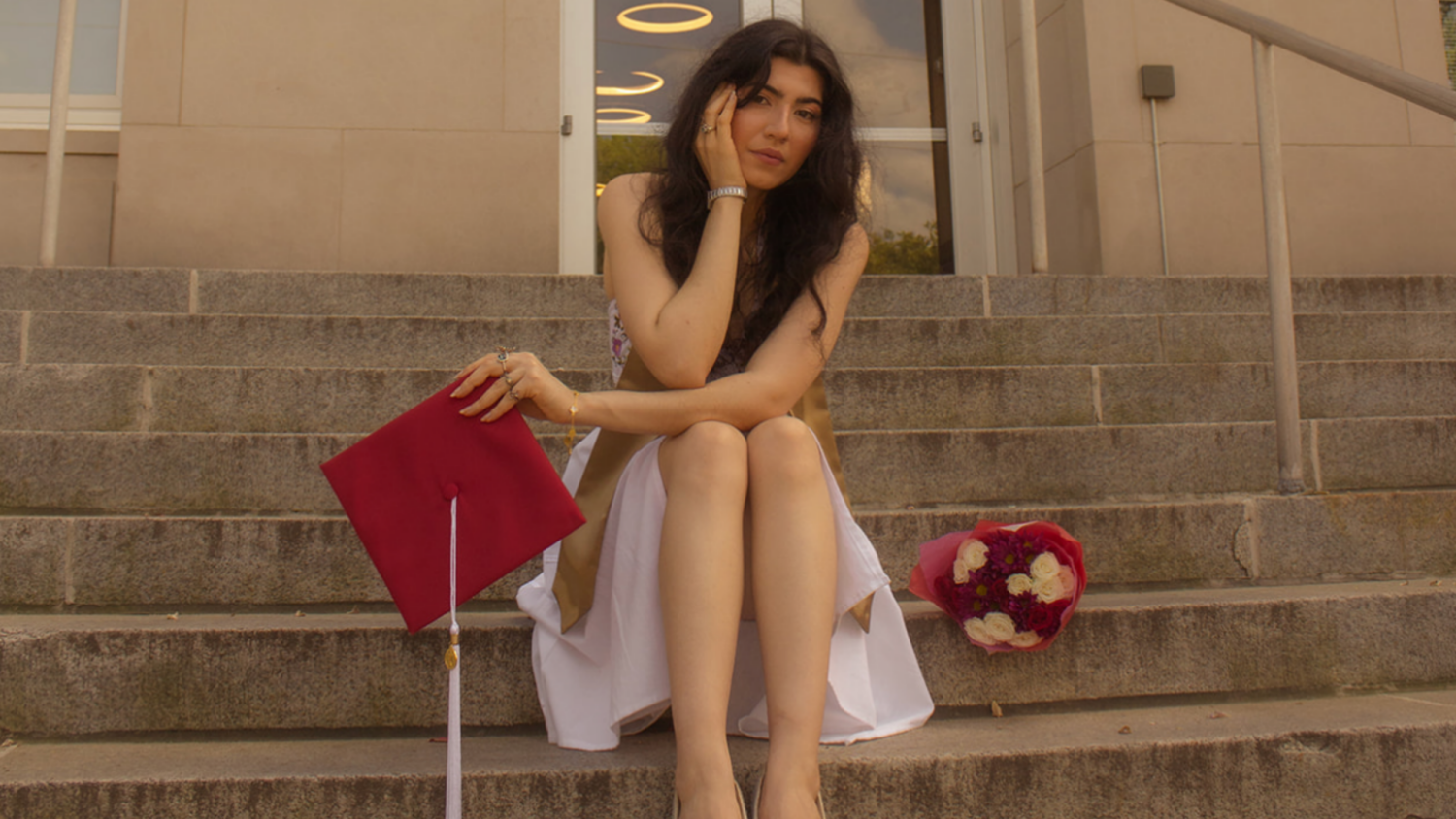 A graduate posing on steps