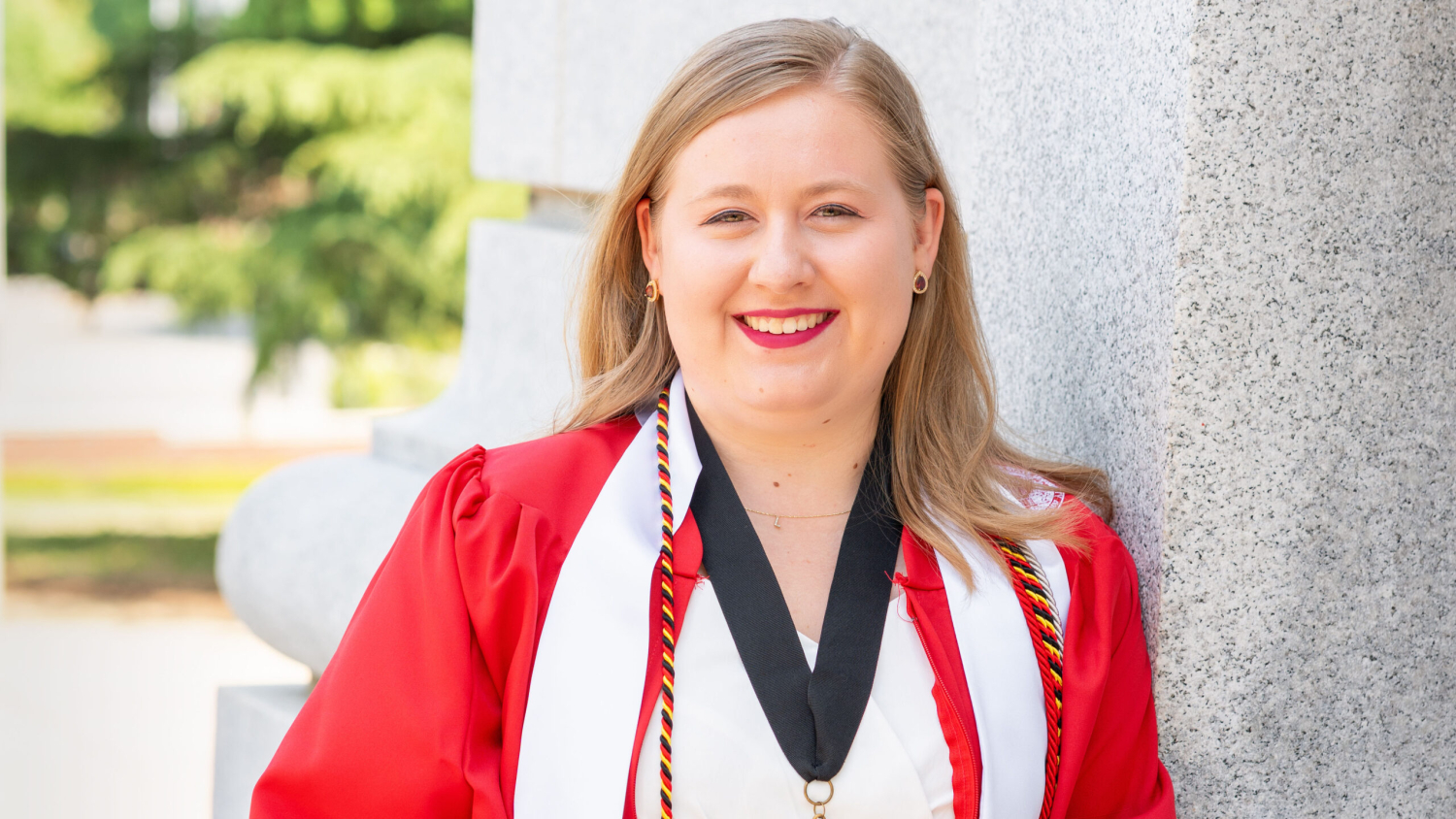 Student standing in front of a wall in her graduation attire.