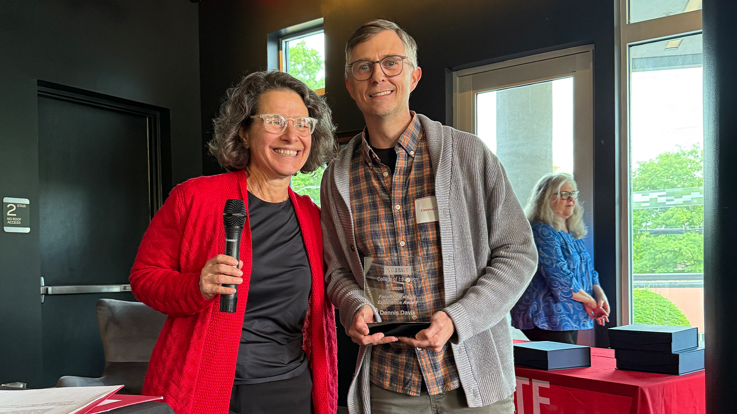 Professor Dennis Davis stands with College of Education Dean Paola Sztajn as he receives an award.