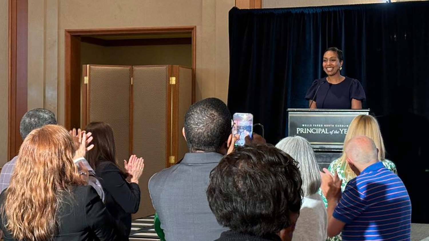 A group of people take photos of Mariah Walker as she receives her Wells Fargo Principal of the Year Award