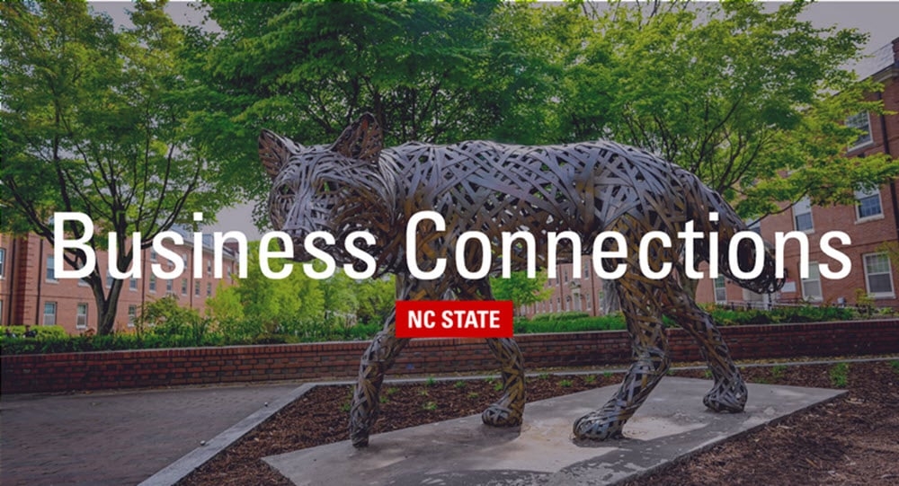 A metal wolf statue on campus with the words "Business Connections" and an NC State brick logo in the foreground