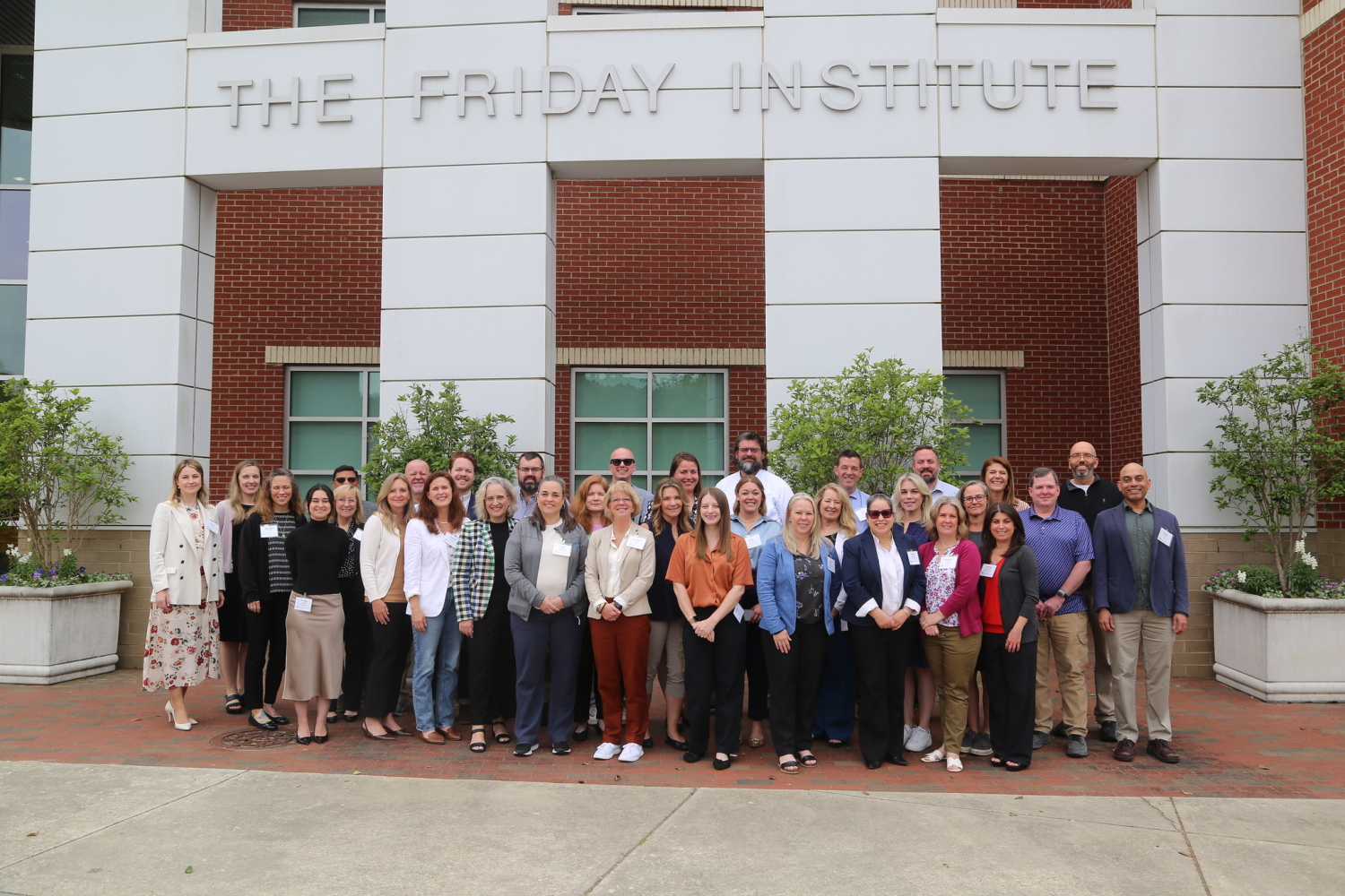 A group poses outside the Friday Institute building--a gridlike building with rectangular blocks and shapes