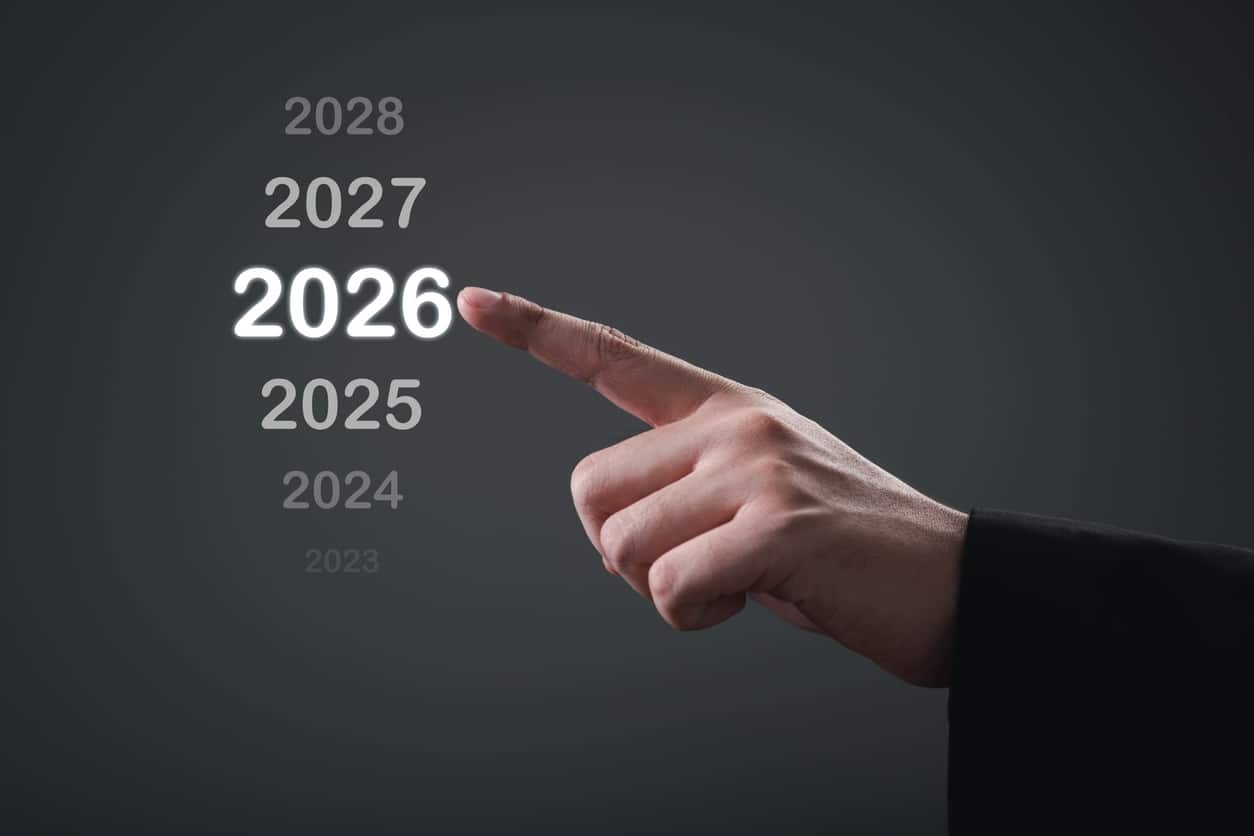 Hand pointing at year 2026 among fading surrounding years, symbolizing future planning, strategic decision and goal prioritization.