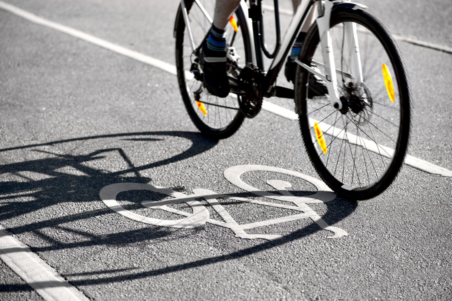 Bicycle riding over a painted bike symbol on asphalt.