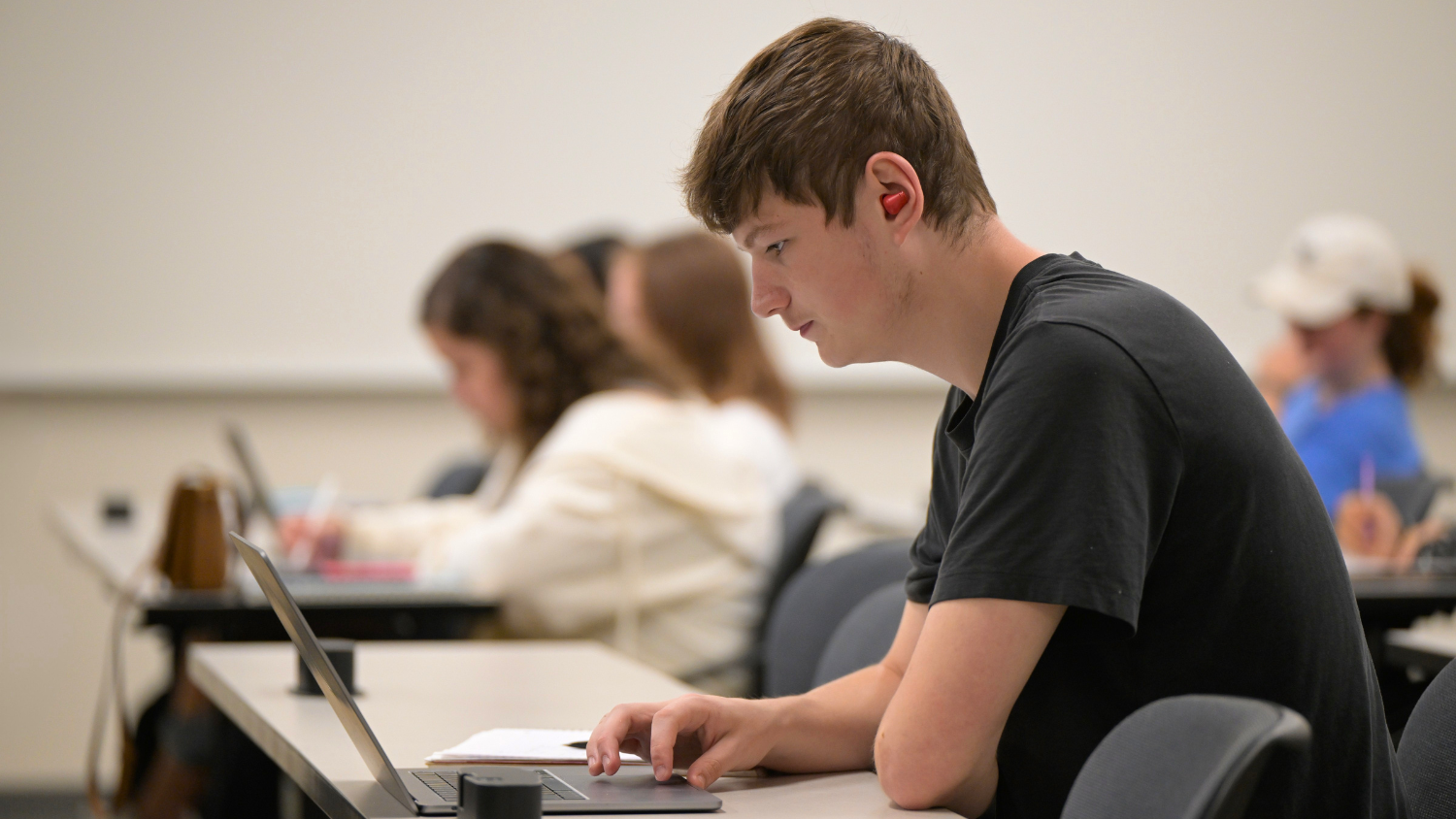 A student attends class in a ClassTech-supported classroom while wearing Bluetooth earbuds.