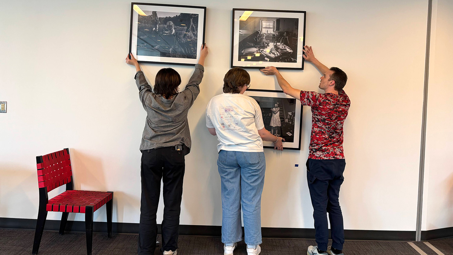 Students hang art on the wall in Talley Student Union.