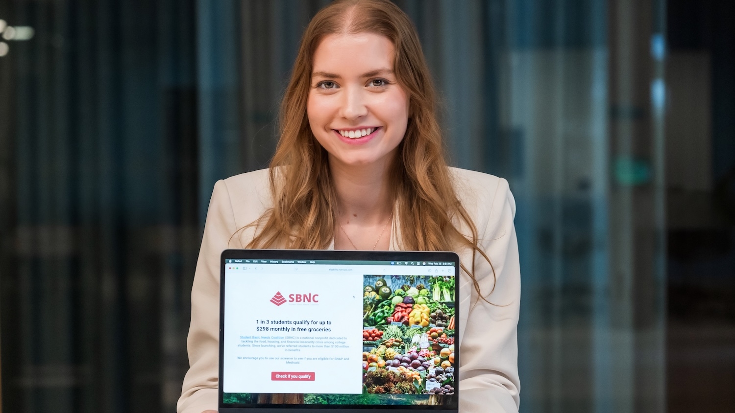Paige Swanstein holds a laptop showing her non-profit's homepage