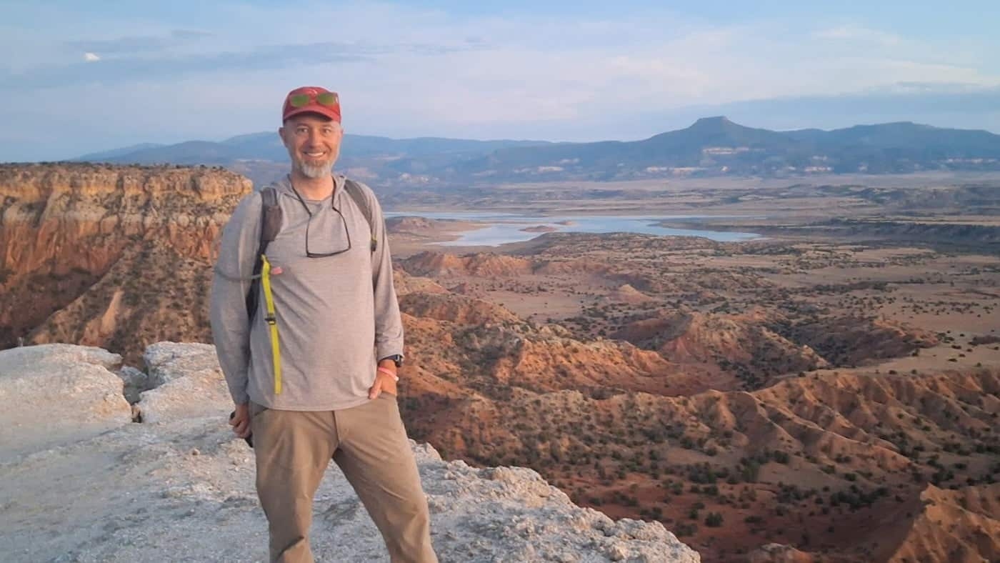 Wegmann stands on a landform overlooking a vast orange valley in New Mexico
