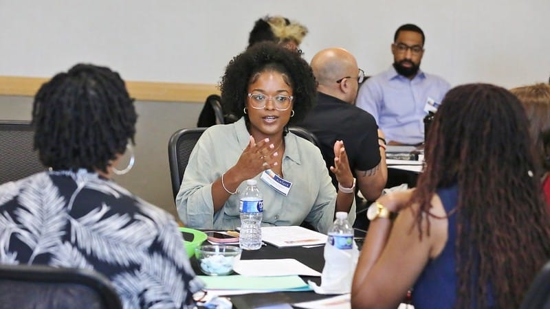 Kailyn Harris-Gilliam sits at a table with other higher education scholars.